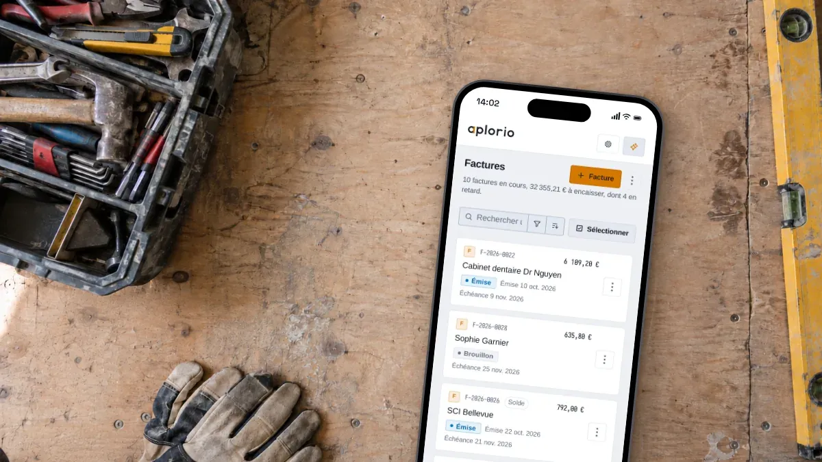 Sur le plancher du camion, entre la caisse à outils et le niveau, un téléphone ouvert sur les factures Aplorio.